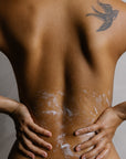 Organic body wash applied to bare back highlighting hydrated skin and natural glow during cleansing ritual.