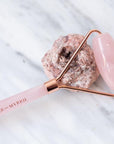 a rose quartz face roller with a rock