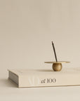 Brass orb incense holder with incense burning, set on a book, adding elegance to a peaceful space