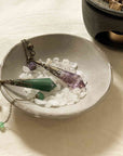 aventurine and amethyst crystal pendulums on the ceramic smudging bowl with white stones