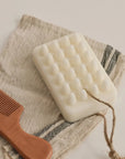 Palo Santo bar soap placed on a linen towel with a wooden comb beside it, creating a simple and calming bath setting