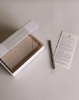 Open box of black copal incense sticks with one stick and ritual instruction card beside it