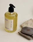 Bottle of 'Bonne Nuit' body wash with a guasha and washcloth on a ceramic plate