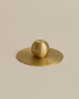bottom view of an orb shaped brass incense holder, highlighting its smooth base and sleek, rounded design