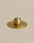 bottom view of an orb shaped brass incense holder, highlighting its smooth base and sleek, rounded design