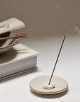 burning cedar incense stick with ceramic incense holder and on the back, several sticks and package on the bowl above the book