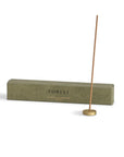 Sandalwood incense stick with a brass incense holder and the packaging behind