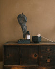 Fraîcheur Aromatherapy Room Spray placed beside a brass incense holder and black ceramic bowl on a rustic wooden cabinet, creating an energizing and balanced ritual mood.