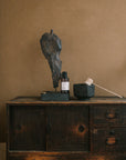 Fraîcheur Aromatherapy Room Spray placed beside a brass incense holder and black ceramic bowl on a rustic wooden cabinet, creating an energizing and balanced ritual mood.