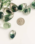 quarter dollar coin and several pieces of green ghost crystals with different size and pattern