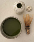 handcrafted ceramic matcha bowl set with matcha liquid, bamboo whisk, ceramic bottle