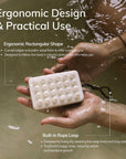 Bar of soap with ergonomic design held by hands in water, text about ergonomic design and practical use