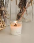 Lighting the mantra mini wellness candle, with a mini basket and dried flowers in a vase placed at the back, creating a cozy, serene atmosphere