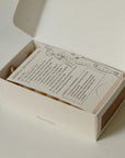 Open box containing a palo santo bar soap with printed instructions about massage routine