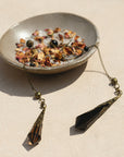 obsidian and smoky quartz crystal pendulums on the ceramic smudging bowl