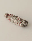 medium sized organic white sage smudge stick tied with red and green string