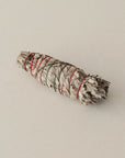 medium sized organic white sage smudge stick tied with red and green string