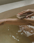 a woman massaging with palo santo exfoliating massage soap in the shower