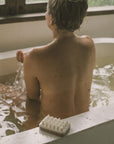 a woman with exfoliating massage soap in the bathtub