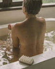 a woman with exfoliating massage soap in the bathtub