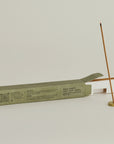 burning palo santo incense stick with brass incense holder and opening package behind