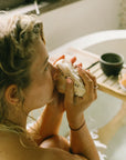 Woman enjoying an authentic Palo Santo wood bath ritual with Cedar and Myrrh, relaxing with natural cleansing aroma