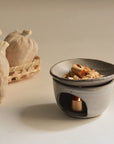 handmade ceramic oil burner with palo santo flakes gently warming over a lit candle light