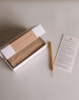 Open box of Palo Santo incense sticks showing scent notes pine, mint, lemon, fireplace, sweet, with ritual instruction card and one incense stick placed beside