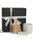 a serene gift set with palo santo bath flakes, ceramic oil burner, and essential oil, presented with a gift box behind