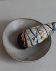 a smudge stick on the sand ceramic incense bowl