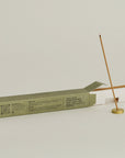 lighting a sandalwood incense stick with brass incesne holder and opening packaging behind