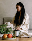 scented candle on the table with fruits, book, and cloth