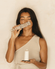 woman performing self smudging ritual with white sage bundle and candle