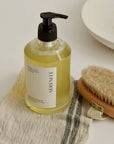 Bottle of Serenite body wash with a brush and towel
