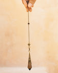 holding a natural smoky quartz crystal pendulum