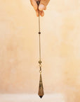 holding a natural smoky quartz crystal pendulum