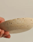 hand holding a travertine incense plate with visible surface texture and natural variations