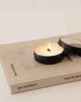 lighting a travel size wellness candle with a lid and placed on the top of the book