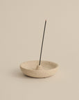 natural travertine plate holding a lit Japanese incense stick for a minimalist ritual setting