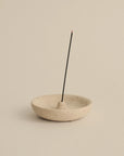 natural travertine plate holding a lit Japanese incense stick for a minimalist ritual setting