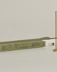 burning white sage incense with a brass holder and opening packaging box behind