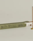 burning white sage incense with a brass holder and opening packaging box behind