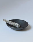white sage smudge stick wrapped in natural twine resting on a simple black ceramic bowl