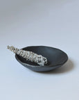 white sage smudge stick wrapped in natural twine resting on a simple black ceramic bowl