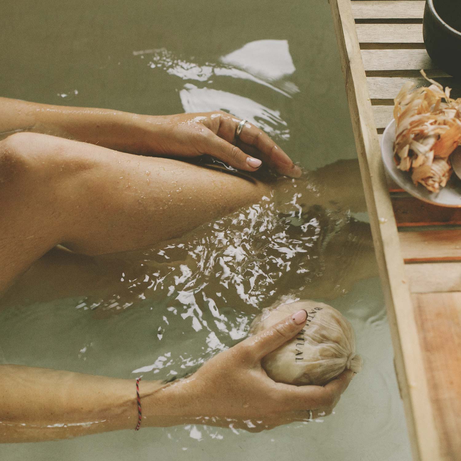 Person holding Hinoki bath flakes with mesh bag on the bath tub.