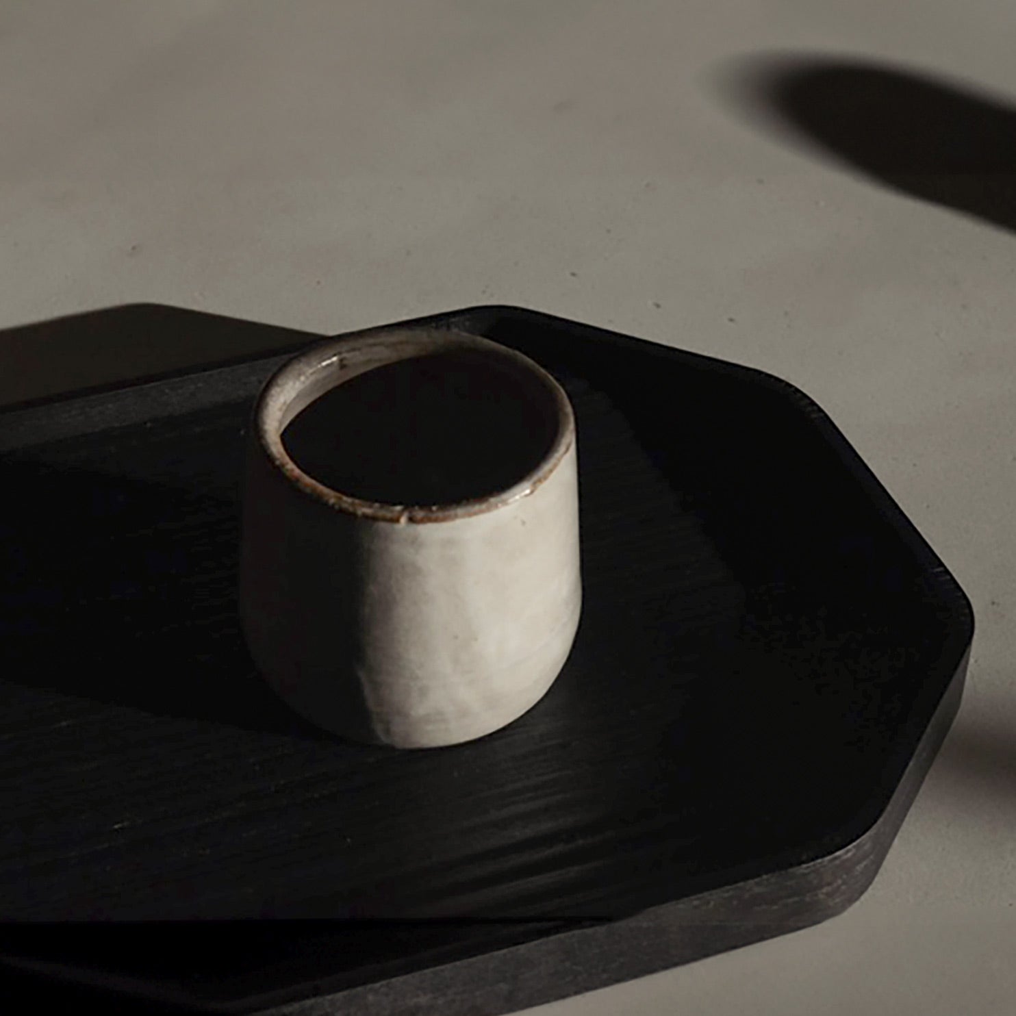 a sand ceramic versatile cup with a black plate