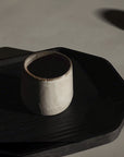 a sand ceramic versatile cup with a black plate