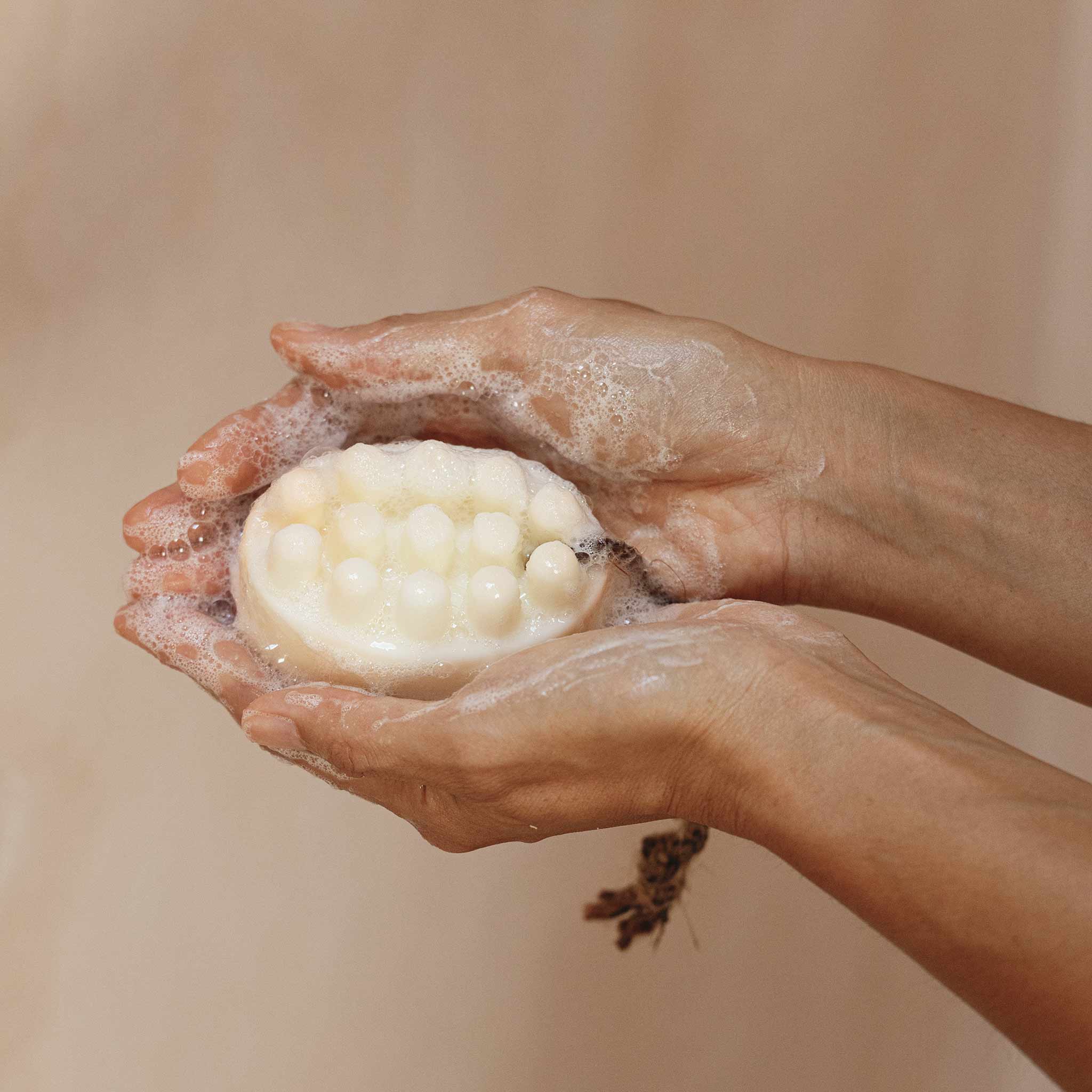 Hands holding a bar of soap with a foam