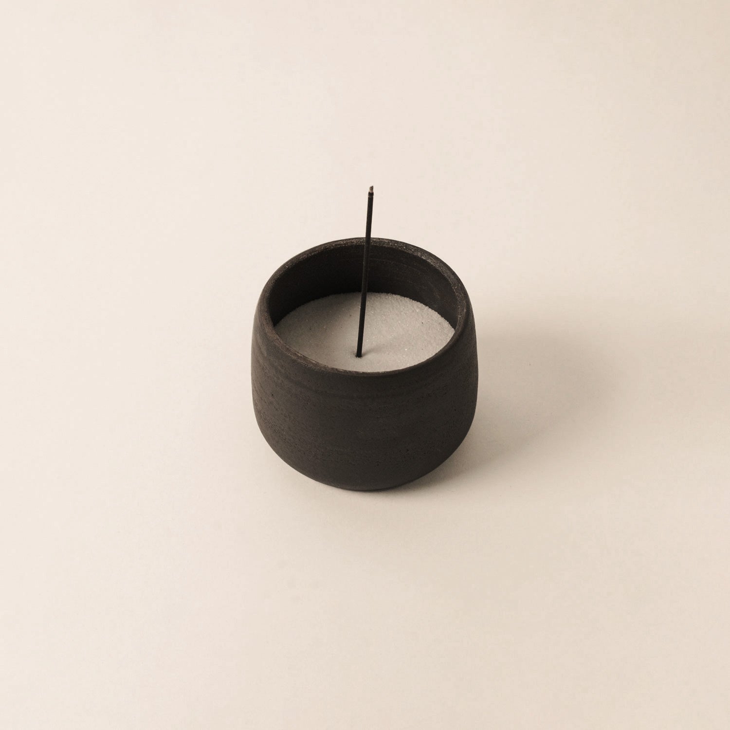 raw black ceramic cup with Japanese Incense filled with sand