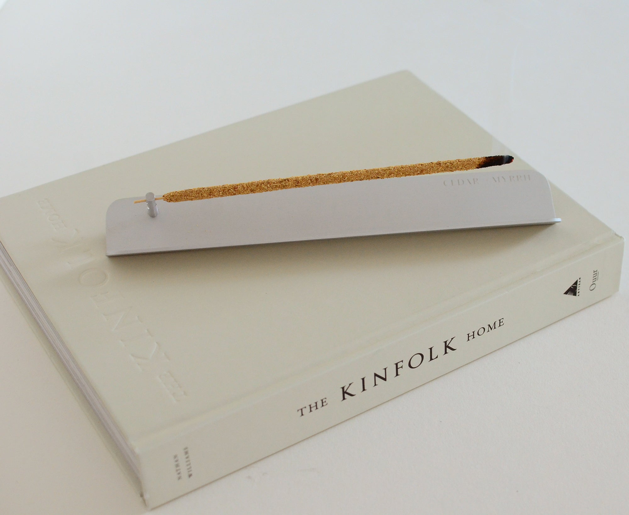 Burning stick incense in minimal aluminum incense holder styled in modern home setting